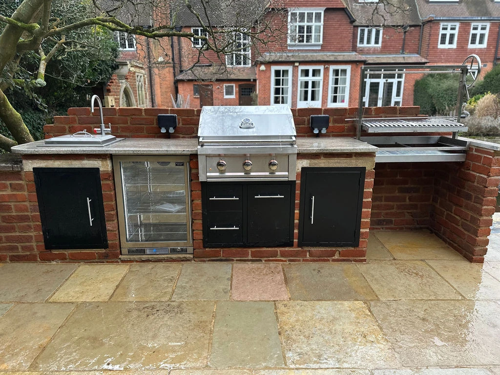 An Argentinian grill, added alongside a gas BBQ, made from reclaimed materials akin to the Cobham property's folly